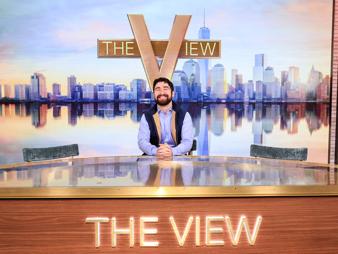 A college student sits at a desk that says THE VIEW on it